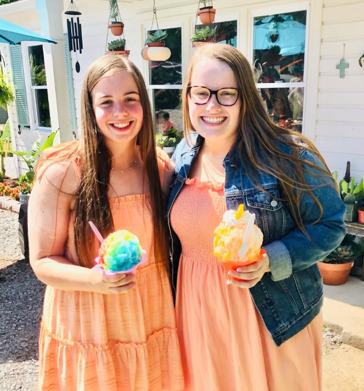Two friends holding rainbow shave ice in front of Hidden Seed Plant Shop